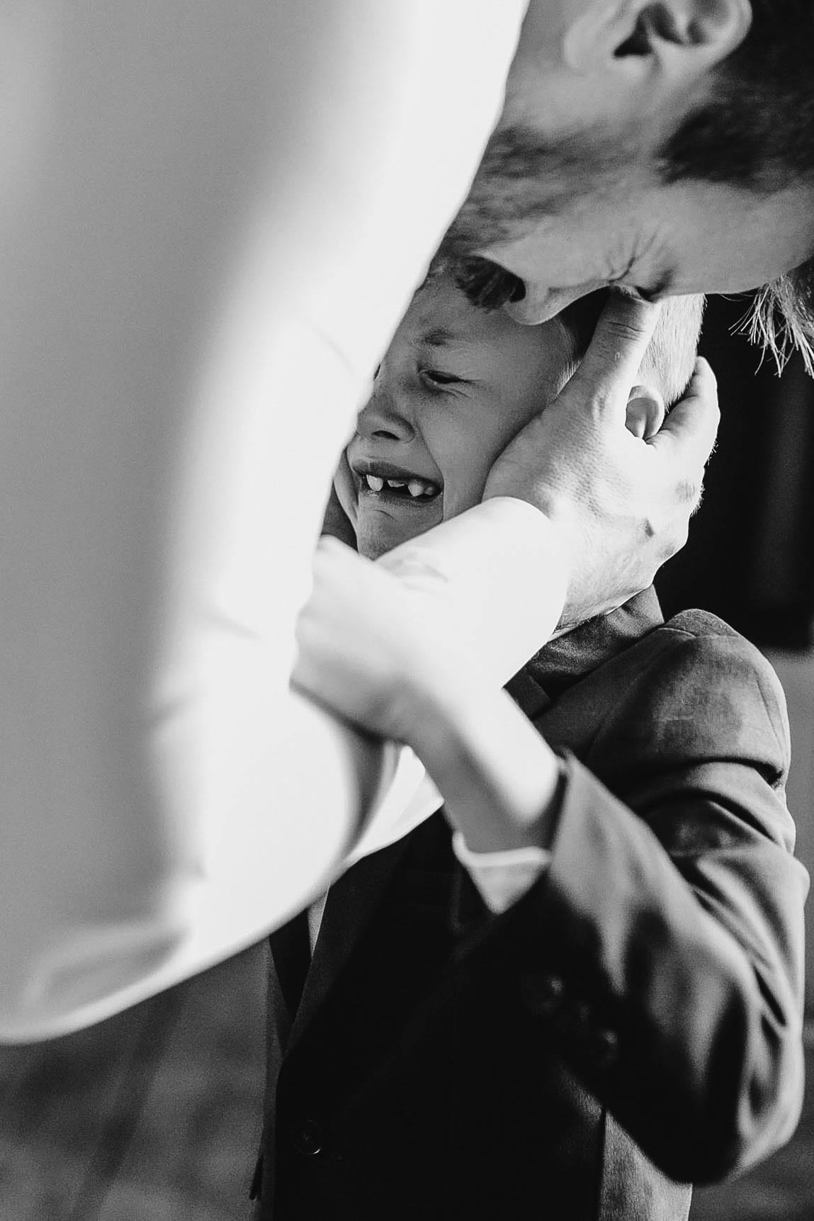 The boy in tears, his father's hands cradling his head