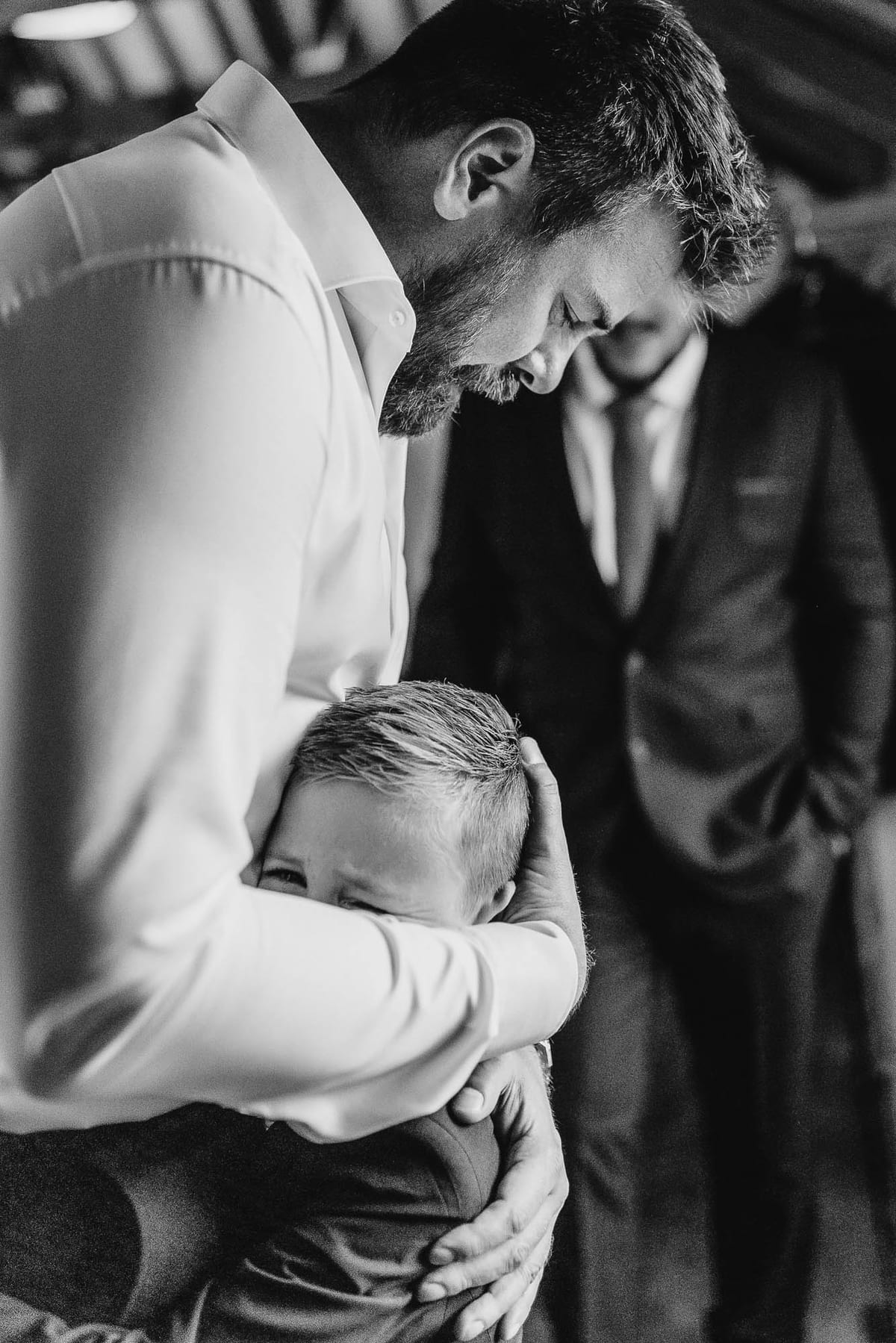 The boy held against his father's chest, the father's head bowed over him
