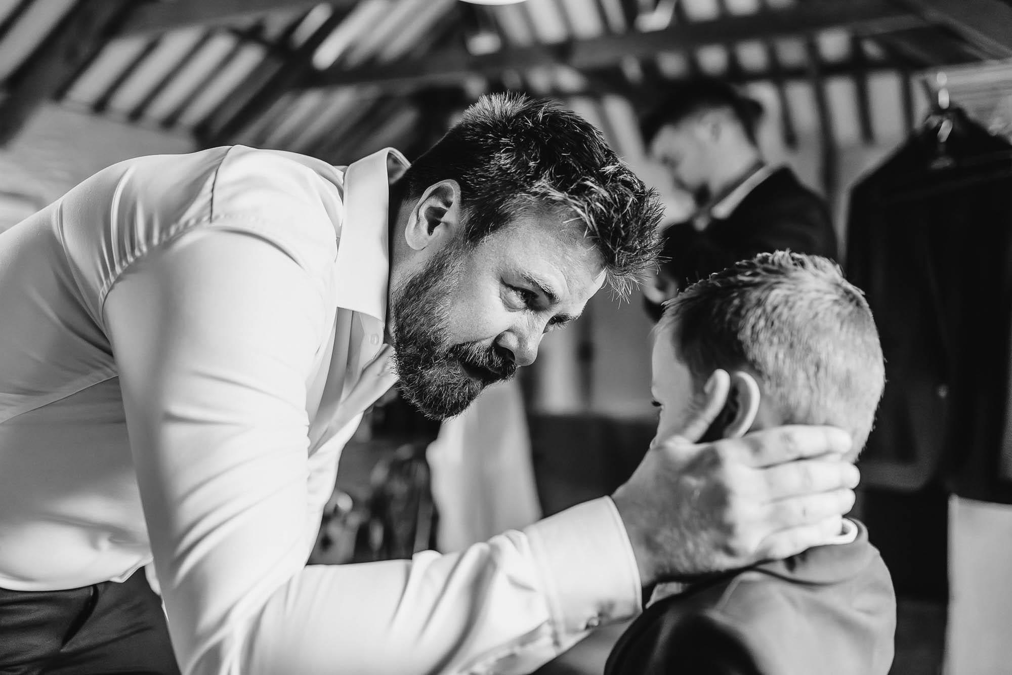 Eye to eye — the father, bent level with his son, steadies him with a hand at the back of his neck