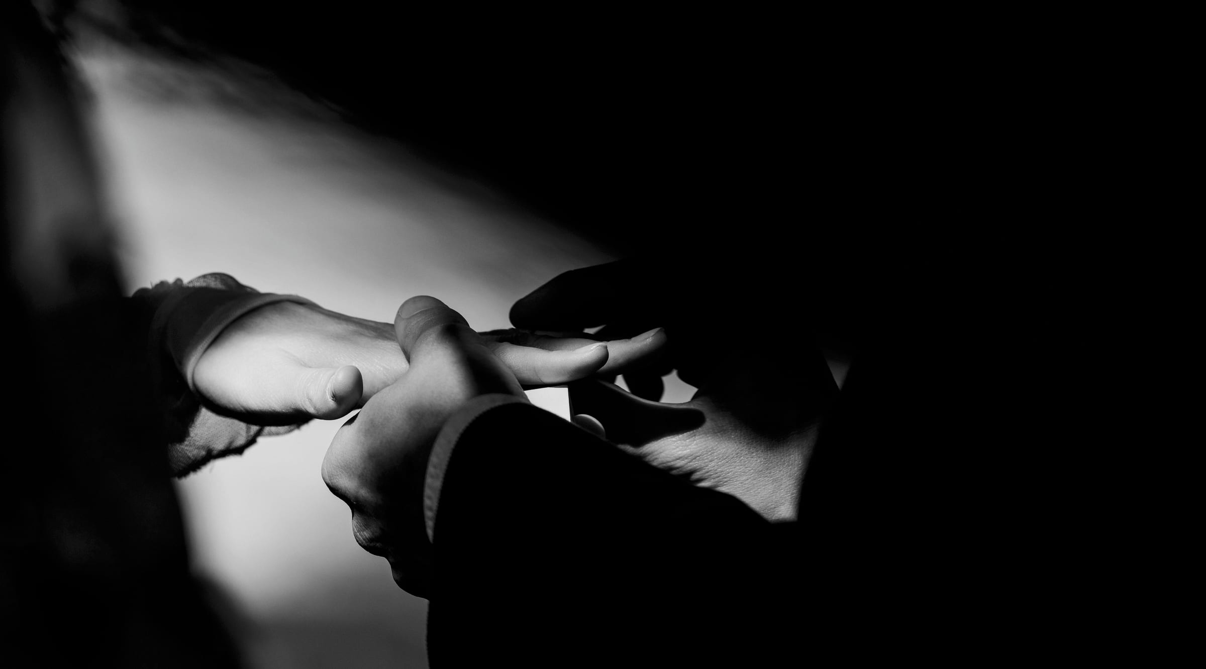 A ring going onto a finger in a shaft of window light — Cornwall wedding ceremony